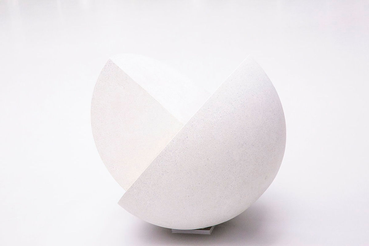 Weißes geometrisches Kunstobjekt aus zwei sich überschneidenden Halbkreisen aus Stein.